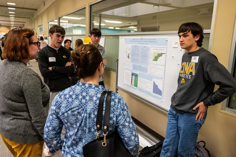 2025 FYS Poster Session student presenters with two people listening
