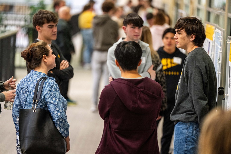 2025 FYS Poster Session students around their poster with others listening