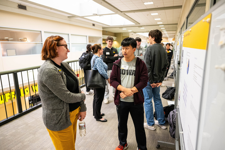 2025 FYS Poster Session Presenter poster unknown title with an audience member listening