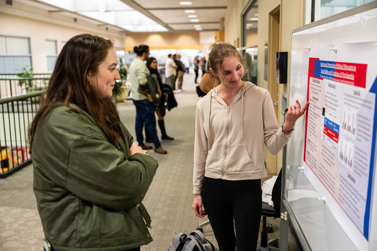 2025 FYS Poster Session presenter with poster title unknown and one audience member listening