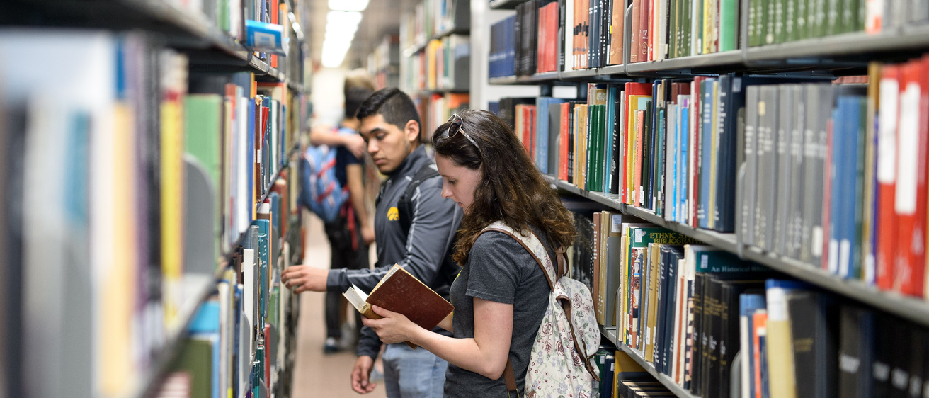 Students in UI library in between shelves of books