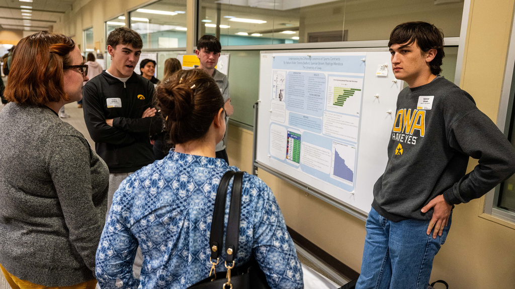 2025 FYS Poster Session student presenters with two people listening